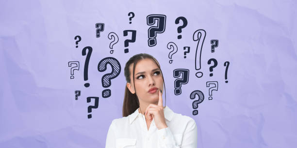 istock Thoughtful woman surrounded by question marks on purple crumpled 2201683757