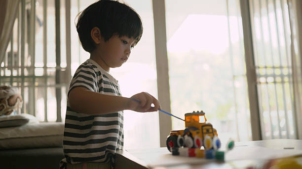 istock Happy Asian boy colored on paper and on a toy construction vehicle. 2201685595