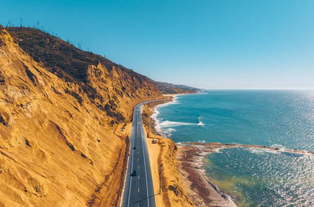 Breathtaking coastal views along the Pacific Coast Highway in California, where a winding road follows the dramatic cliffs and blue ocean. This iconic scenic drive captures the beauty of the West Coast’s rugged shoreline.