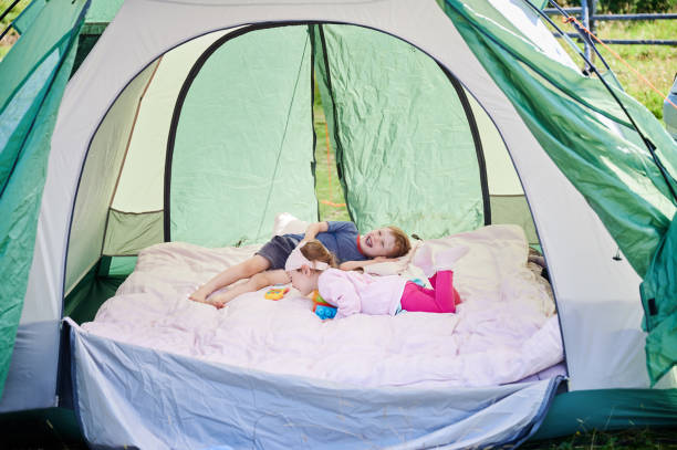 istock Two young children relax inside spacious green tent. 2201687857