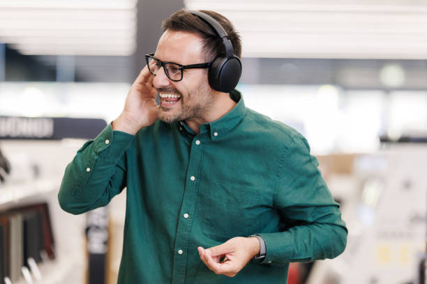 istock Man enjoying music with wireless headphones in a modern electronic store 2201688332