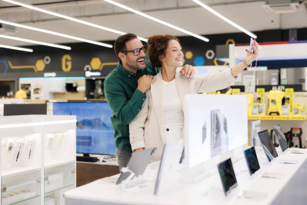 istock Mid adult couple testing phone camera in electronic store 2201688534