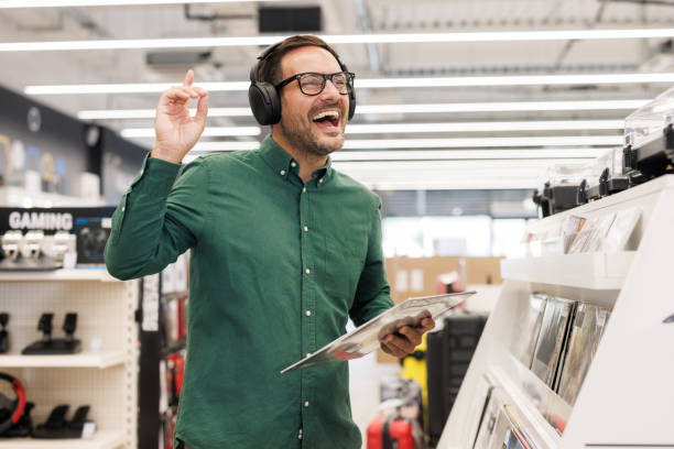 istock Man enjoying music on headphones in a modern electronics store. 2201688601
