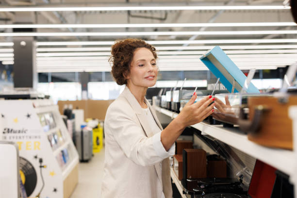 istock Woman browsing audio devices in a modern electronics retail store 2201688652