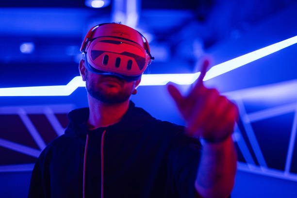 istock Cool tech man with VR headset glasses controls virtual menu in dark room with neon light 2201688827