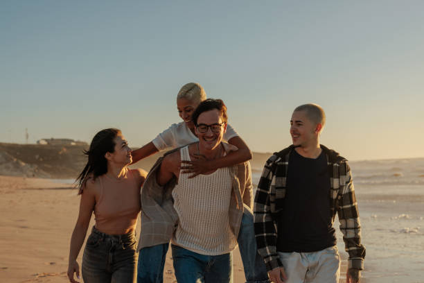 istock Happy friends walking and having fun on the beach at sunset 2201688930