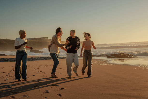 istock Friends running and having fun on the beach at sunset 2201688938