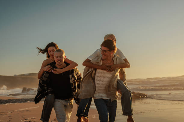 istock Friends giving piggyback rides on beach at sunset 2201688940