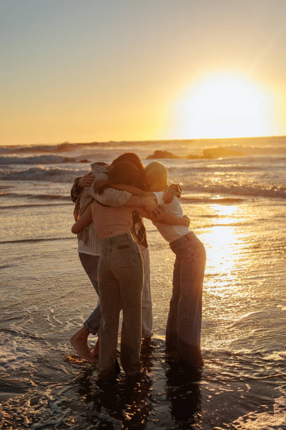 istock Friends hugging at sunset on the beach, enjoying precious moments together 2201688949