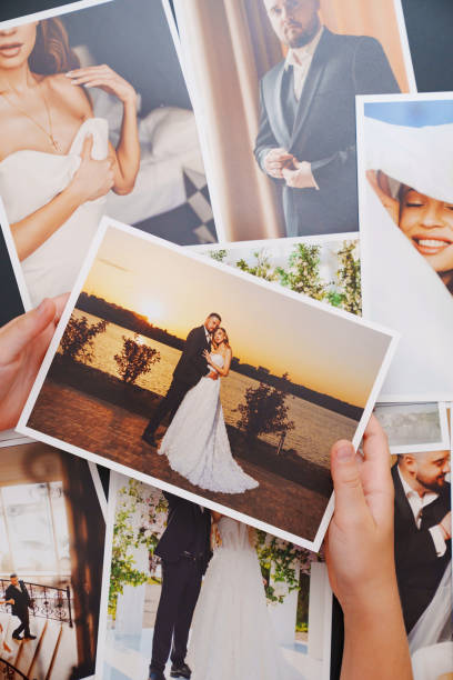 istock women's hands put on the table and show wedding photos. 2201691356