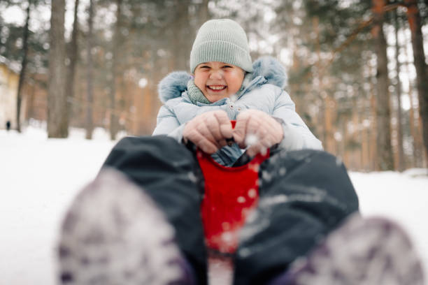 istock Happy child enjoying sledding down snowy hill in winter forest 2201691711
