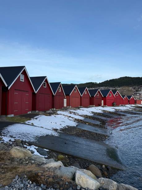 istock Red boathouses along a snowy shoreline. 2201696373