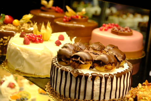 istock White chocolate, profiterole and strawberry cakes in a pastry shop window 2201696392