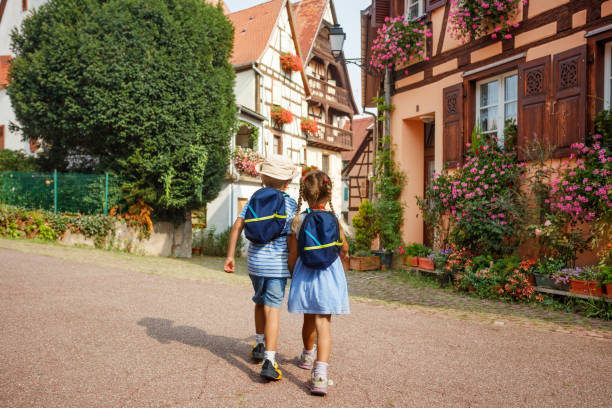 istock Two children walk holding hands through sunny village Eguisheim 2201697242