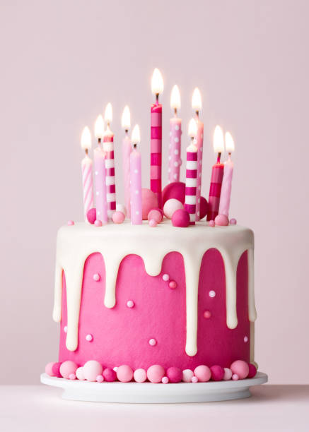 istock Pink celebration birthday cake with candles and drip icing 2201697539
