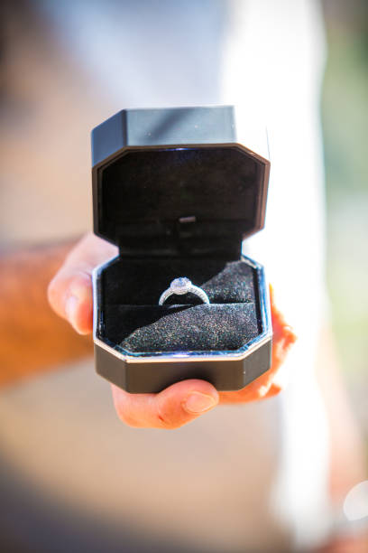 Wedding ring with diamonds in black elegant box. Man holds an open jewellery box with expensive proposal ring. Asking to marry him, a traditional way to make a proposal