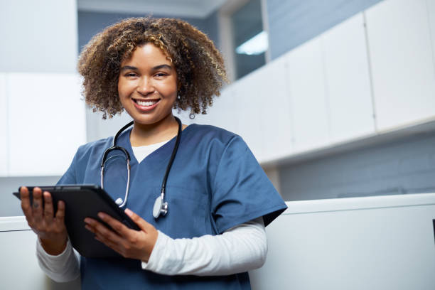 istock Smiling Medical Professional Wearing Scrubs Holding a Digital Tablet in a Modern Workplace Setting 2201703335