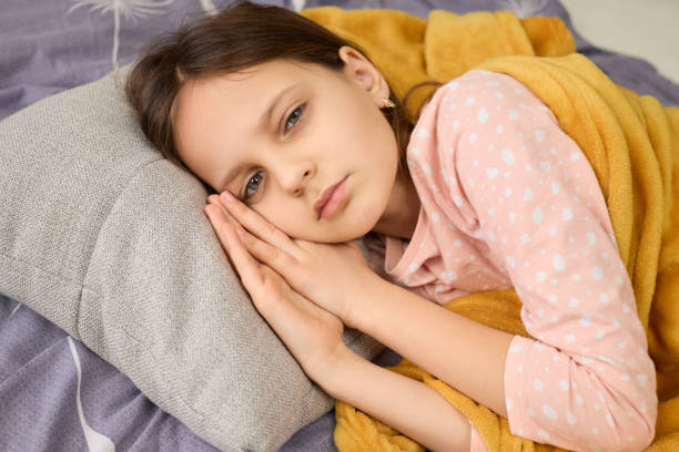 istock A young girl is resting on a gray pillow, looking contemplative. She is wrapped in a soft blanket, reflecting a peaceful and cozy afternoon atmosphere at home 2201705302