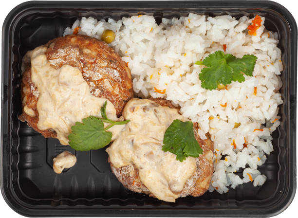 istock Rice with meatballs in a disposable rectangular plastic black lunch box top view on a white background 2201705630
