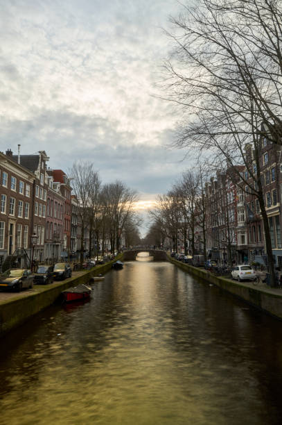 istock Canal reflecting golden light at sunset in amsterdam, netherlands 2201705903