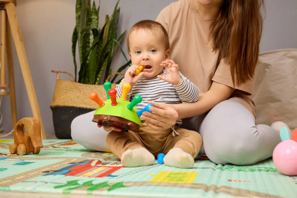 istock A young child sits on a soft play mat in a cozy room, engaged with a colorful toy while a parent sits beside them, providing a nurturing atmosphere for playtime 2201711637