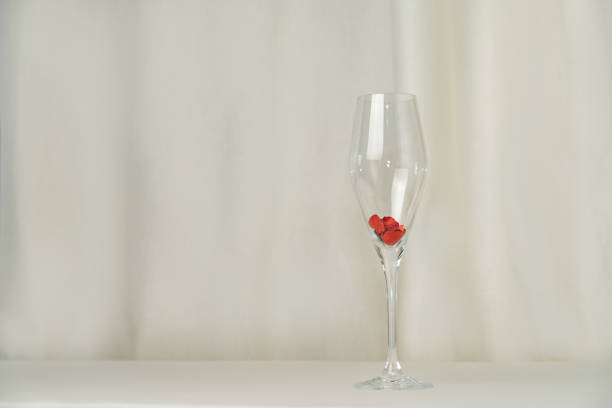 istock Wine glass with heart confetti on cream background 2201711699
