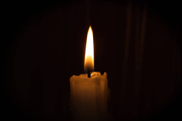 istock Single candle flame illuminates the darkness creating serene, comforting atmosphere with warm glow 2201713415