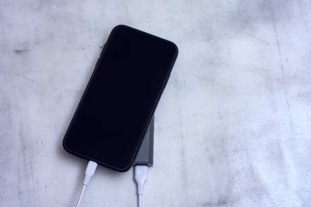 istock Smartphone with black screen is charging from a portable power bank on a marble table. 2201713548