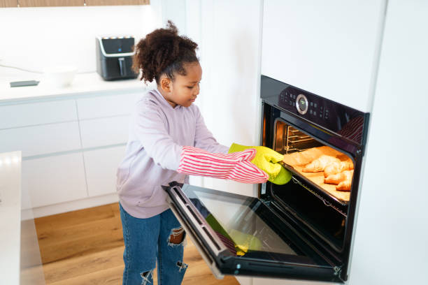 istock Young Girl in Pink Sweater Baking Cookies in Modern Kitchen 2201715634