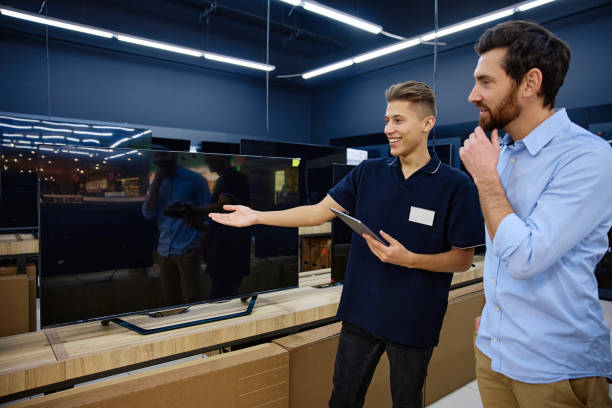 istock Sales Associate Expertly Demonstrating Exciting TV Features in a Busy Electronics Store 2201717763