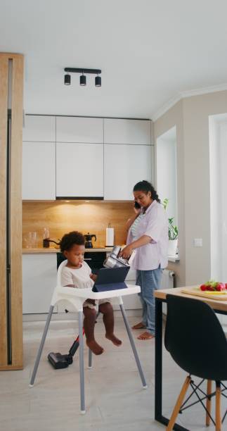 istock The baby is watching a cartoon while mom is cleaning 2201718559
