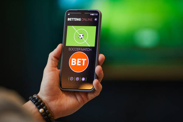 istock Hand Holding Smartphone Displaying Soccer Betting Application 2201721433