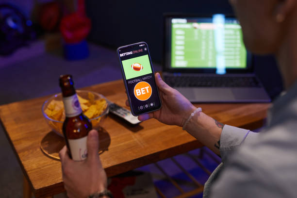 istock Betting Online Hand Holding Smartphone and Beer Bottle 2201721584