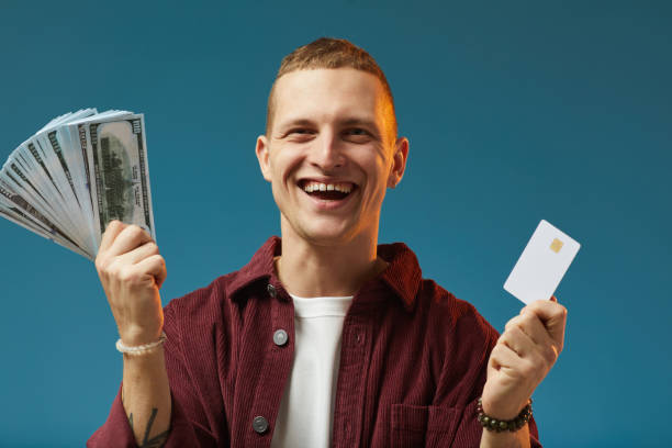 istock Holding Cash and Credit Card with Cheerful Expression 2201722156
