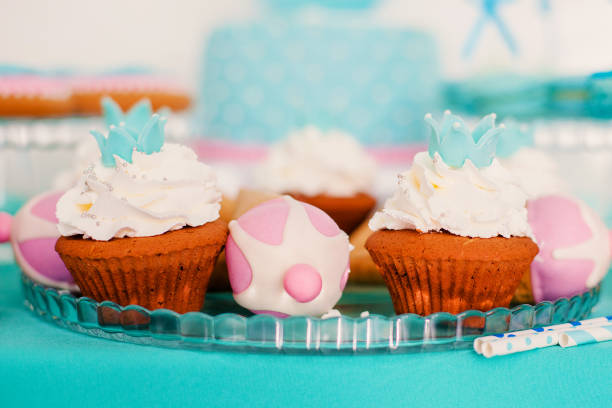 Stock photo showing close-up view of a single freshly baked, homemade, red velvet cupcake in paper cake case. The cup cake has been decorated with a swirl of ombre effect pink piped icing.