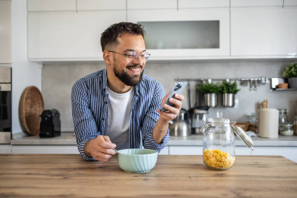 istock Happy man enjoying breakfast and browsing social media in a modern kitchen 2201724013
