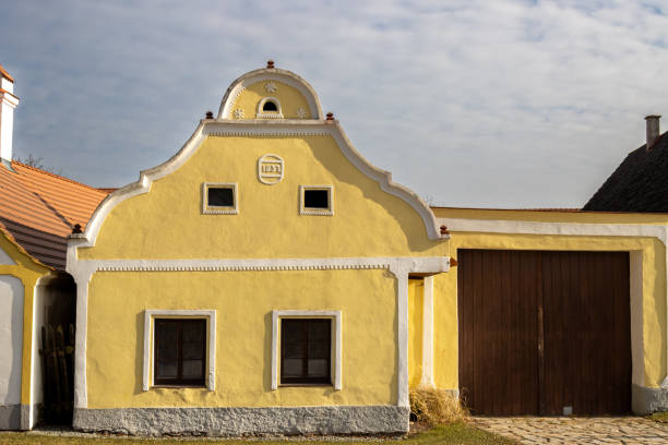 Yellow historical house built in style peasants baroque in 1831.. Very well preserved building, part of UNESCO World Heritage Sites. Blue sky with white clouds. Holasovice, Czech repbulic.