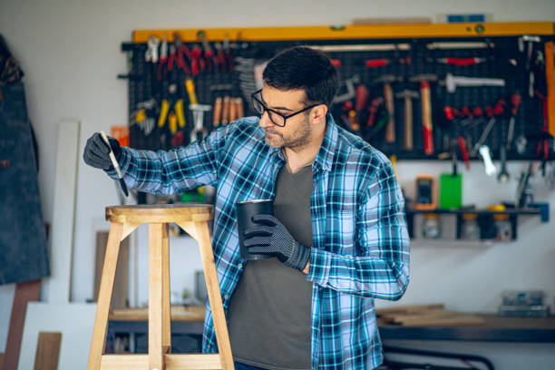 istock Craftsman painting his wooden stool product in his workshop 2201726178