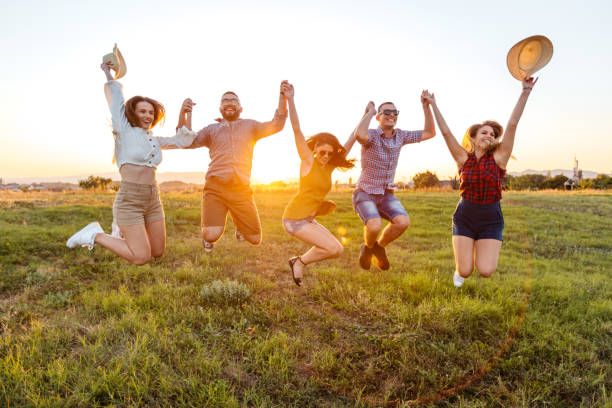 istock Group Of Friends Jumping In The Field At Sunset 2201726524