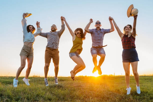 istock Group Of Friends Jumping In The Field At Sunset 2201726548