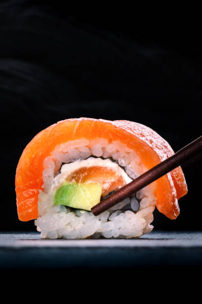 istock Salmon sushi with avocado and cream cheese, uramaki roll on black with copyspace 2201727664
