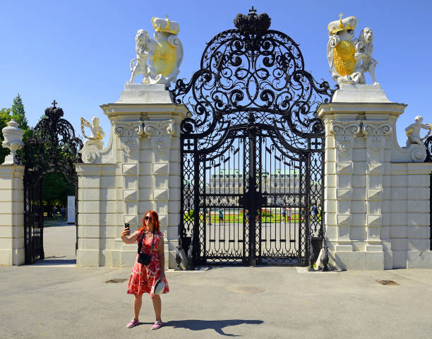 Vienna, Austria, Belvedere garden – Vienna is UNESCO World Heritage Site - Young woman taking a selfie in front of the gate to the castle gardens