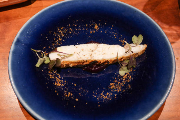 close up of grilled flounder fish with purple carrot sauce and cumin power in a blue plate with copy space