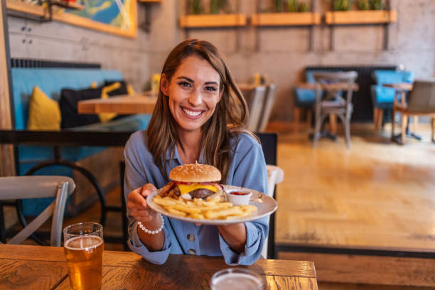 istock Young woman holding a plate with a tasty burger 2201728439
