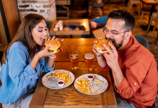 istock Couple eating burgers at the restaurant 2201729099