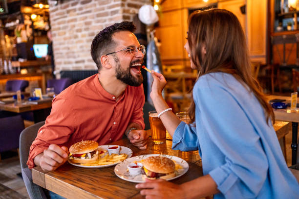 istock Joyful couple eating burgers at the restaurant 2201729140