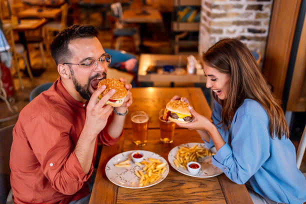 istock Couple eating burgers at the restaurant 2201729158