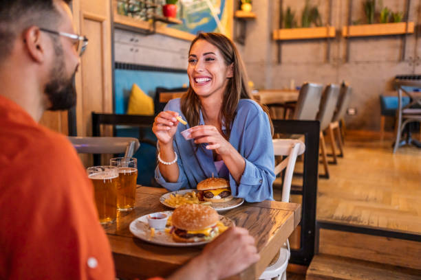 istock Joyful couple eating burgers at the restaurant 2201729234