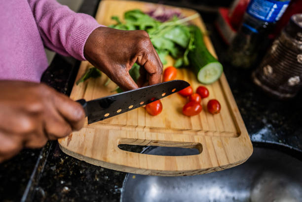 istock Close-up of woman chopping cherry tomatoes 2201729325