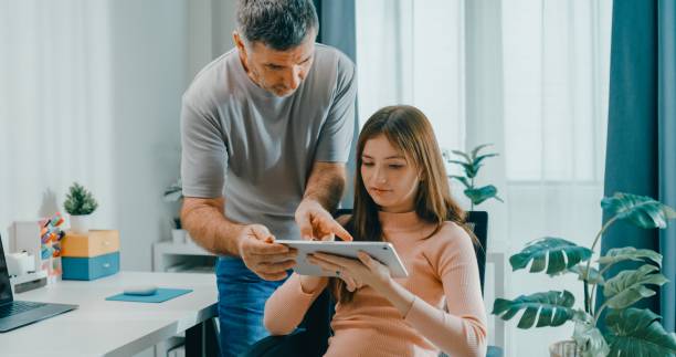istock Senior father assists his daughter with her work on digital tablet, promoting family bonding and technology use in learning at home. Lifestyle family. 2201729385